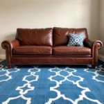 Brown couch with blue area rug