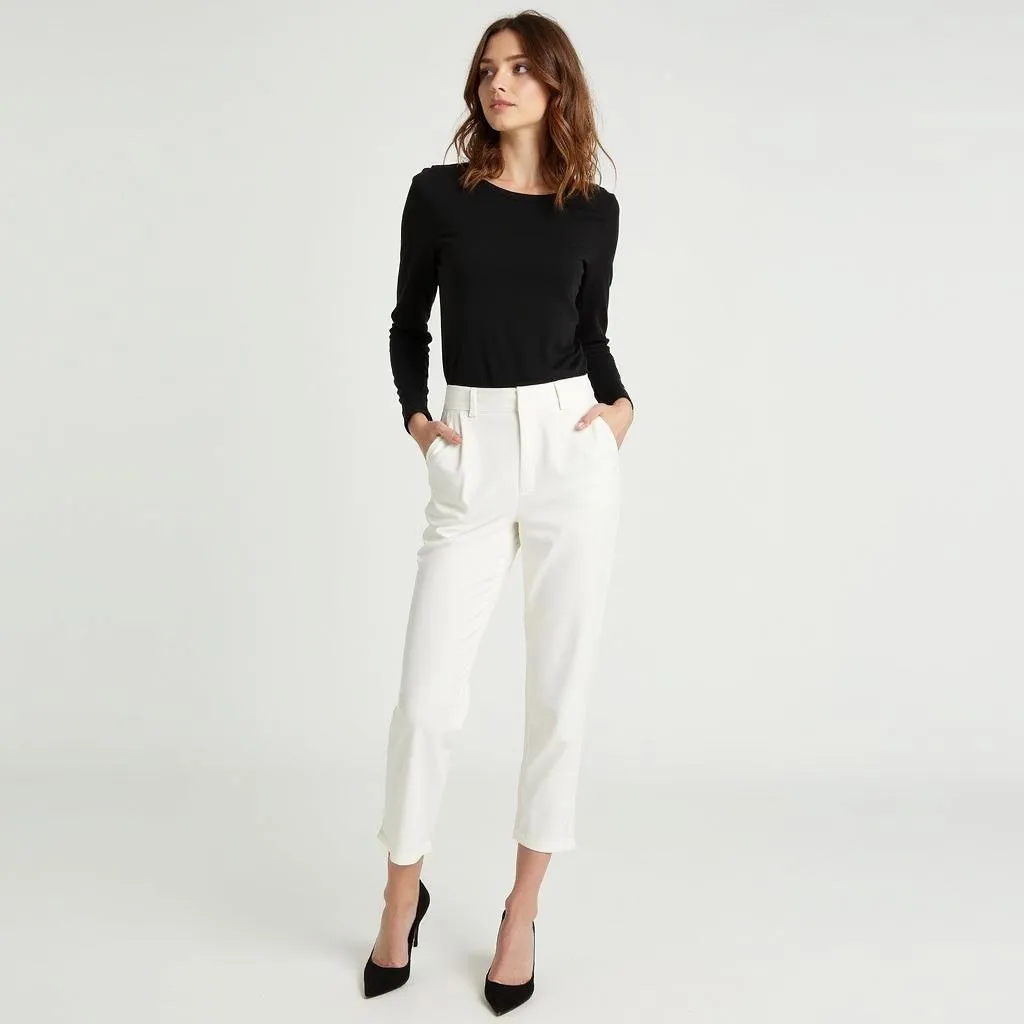 A woman wearing white pants with a black top and heels.