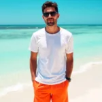 Man wearing bright orange shorts and a white shirt at the beach